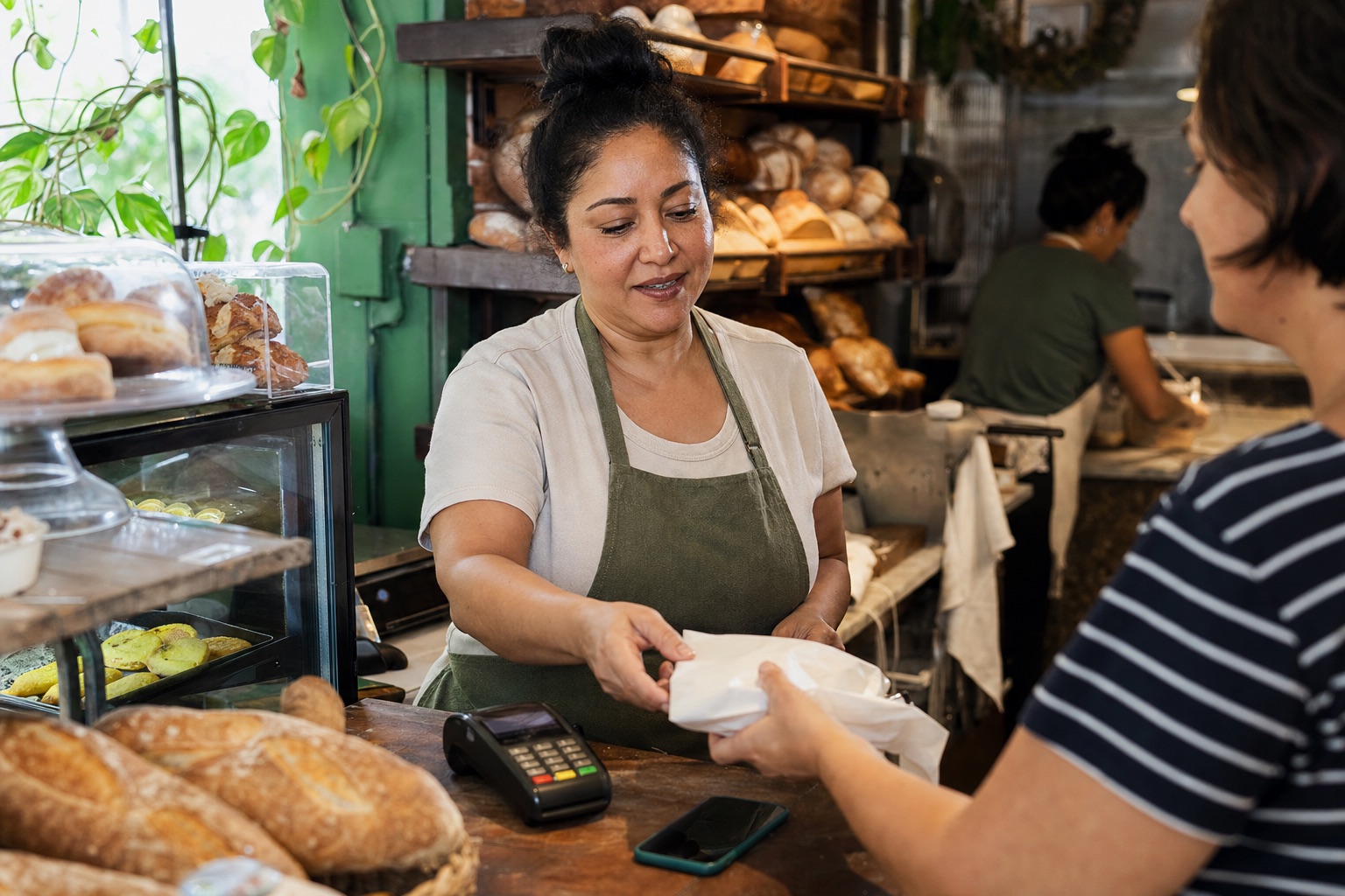 Empreendedora atendendo uma cliente no balcão de sua padaria